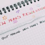 A notebook with 'New Years' Resolutions" written at the top, and the first line being "Stop making New Years' Resolutions"