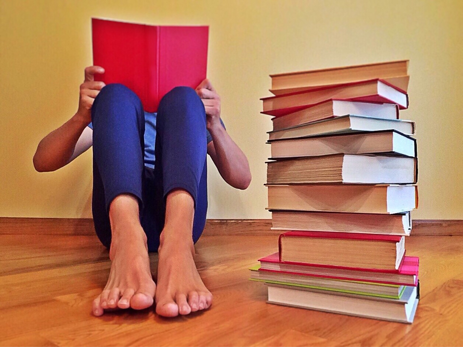 A reader sits next to a stack of books.